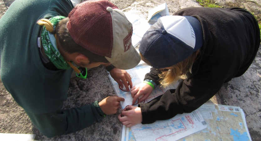 Two people examine a map on the ground.